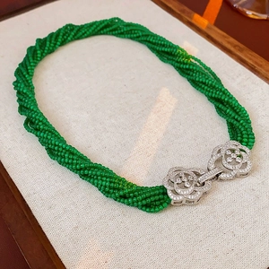 Close-up of double flower zircon clasp on a multilayered green bead necklace