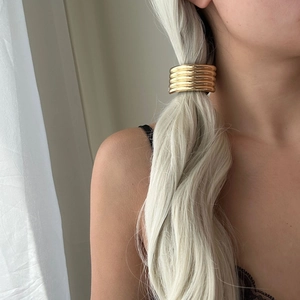 Detailed view of layered gold alloy ponytail cuff hair wrap on blonde hair accessory