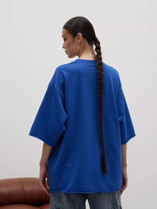 Vista posteriore della t-shirt oversize in pesante cotone blu reale con spalle calate