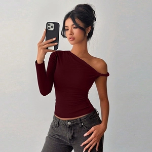Detail of burgundy asymmetric one-shoulder long sleeve top with twisted shoulder knot design