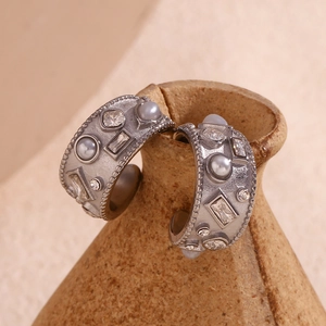 Close-up of vintage silver C-shaped hoop earrings with grey pearls and geometric crystals