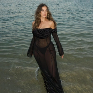 Dettaglio del vestito lungo in rete nera trasparente con spalle scoperte in spiaggia