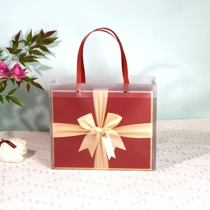 Detail of red square gift box with champagne gold bow and translucent tote bag