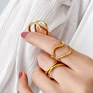 Set of four gold intertwined wavy rings and minimalist bands on hand with white background