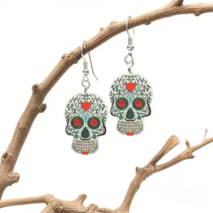 Detail view of Day of the Dead skull earrings with floral relief on a wooden branch