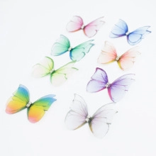 Vue détaillée de broches papillon en organza coloré avec strass et bords métalliques