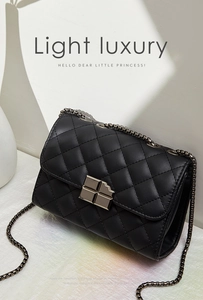 Detail of black quilted chain bag featuring a unique cross-shaped geometric metal clasp
