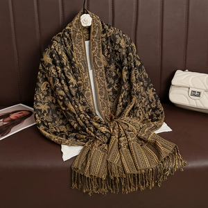 Detail shot of paisley patterned pashmina shawl with fringes on a leather sofa