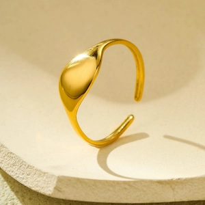 Detail of 18k gold irregular geometric signet ring on textured stone base
