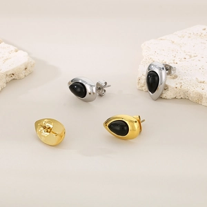 Gros plan de boucles d'oreilles goutte or et argent avec pierre œil de chat noire sur pierre
