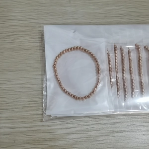 Detail view of rose gold beaded elastic bracelets in clear individual plastic packaging