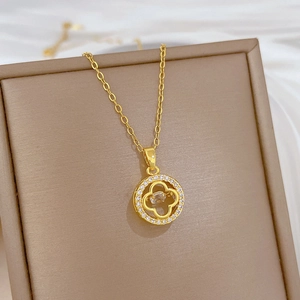 Macro shot of gold four-leaf clover pendant with glittering crystals and hollow design