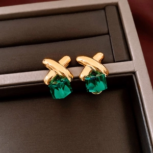 Close-up of vintage gold cross earrings with square green crystal in a velvet jewelry box