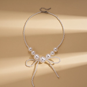 Detailed view of baroque faux pearl necklace with an elegant beaded bow fringe charm