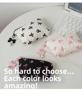 Three quilted bow makeup bags with pearl charms and metal zippers on a white desk