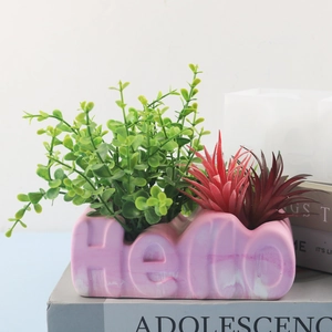 Detail of pink marble Hello letter flower pot with lush artificial succulent plants