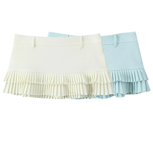 Détail de mini-jupes plissées superposées en beige et bleu clair avec passants