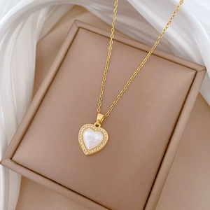 Detailed close-up of heart-shaped gold necklace with mother of pearl and cubic zirconia
