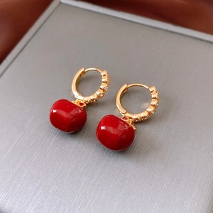 Macro detail of 18K gold plated hoop earrings with red pendants on a jewelry box