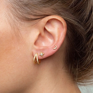 Detail of S925 silver hoop earrings with star and moon studs set in gold finish