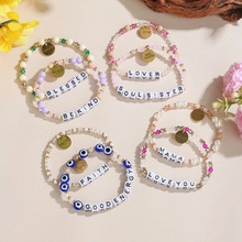 Platte weergave van kleurrijke kralenarmbanden met gouden bedeltjes en inspirerende letters
