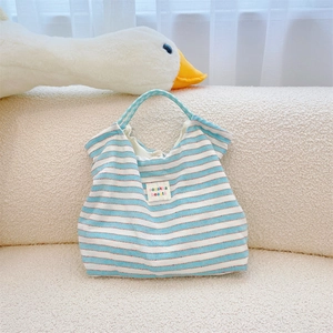 Detail of blue and white striped canvas tote bag with a woven brand logo patch
