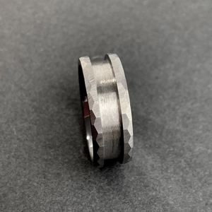 Detailed close-up of hammered and brushed gray tungsten steel ring with beveled edges