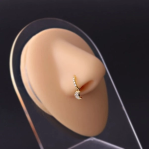 Detail showing a golden nose ring with crescent moon zircon pendant on a display model