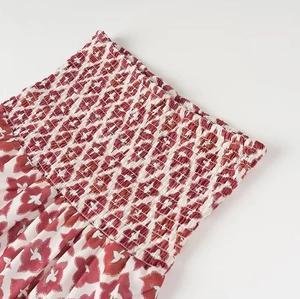 Detail of red and white floral print fabric with elastic smocking texture and pattern
