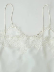 Détail de la dentelle blanche élégante et du tissu satiné sur une robe à bretelles