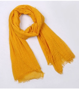 Detailed view of yellow voile scarf featuring crinkled texture and frayed fringe edges