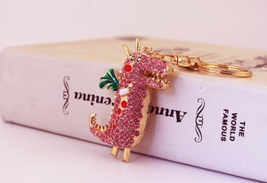 Macro d'un porte-clés dragon doré orné de cristaux roses brillants et détails verts