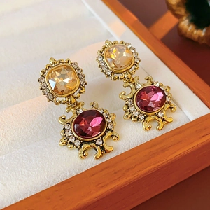 Detail view of vintage gold earrings with champagne and purple gems and zircon inlay
