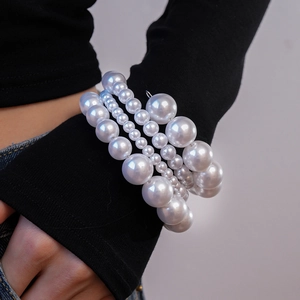 Gros plan d'un bracelet multicouche en perles synthétiques de tailles variées au poignet