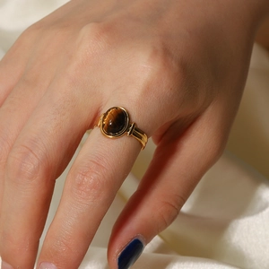 Close-up of vintage gold titanium ring with oval brown tiger eye stone on silk background