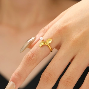 Detail showing elegant gold mermaid tail ring with pearl on woman hand