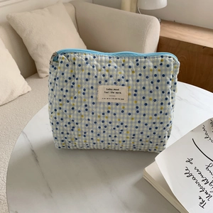 Detailed view of quilted makeup bag with blue polka dots and checkered floral pattern