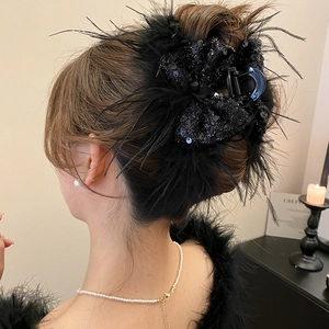 Detailed view of large black hair claw clip with elegant feathers and sequins on hair