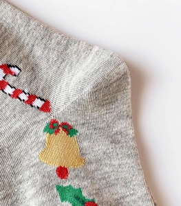 Macro view of Christmas knit socks featuring festive candy canes and bell embroidery patterns