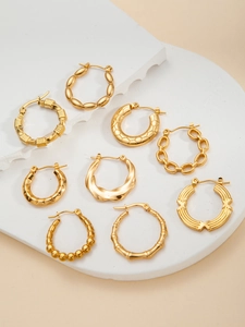 Detail of nine different gold-plated titanium steel hoop earrings on a white stone pedestal