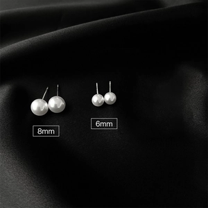 Detailed comparison of 8mm and 6mm white pearl studs on a luxury black silk background
