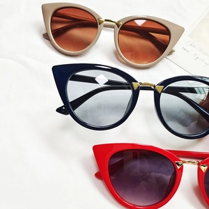 Three retro cat-eye sunglasses in khaki, navy, and red displayed on white fabric