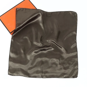 Detailed view of glossy dark brown silk scarf with hemmed edges and orange gift box