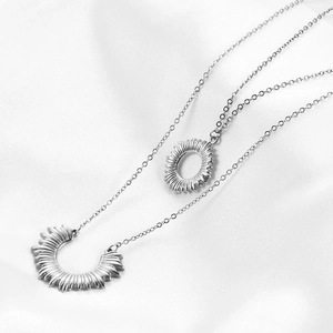 Detail of silver double-layered stainless steel necklace with sun burst circle charms