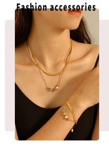 Detail of layered gold snake chain necklace and bracelet with colorful heart charms