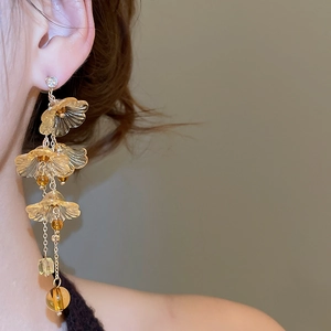 Detail of elegant amber resin flower earrings with long gold tassel and crystal studs