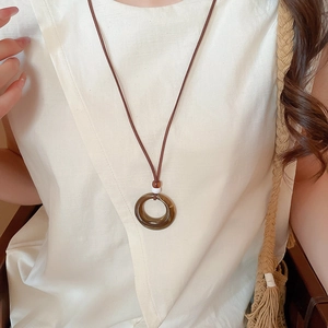 Macro shot of circular resin pendant necklace on a linen top with vintage aesthetic