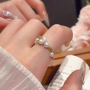 Close-up of minimalist gold ring with five pearls on a pearl-textured band for women