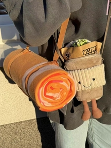 Detail of coffee cup plush carrier bag with strap holding a small potted plant inside