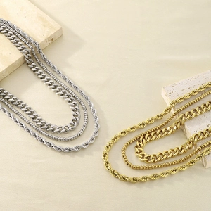 Detailed view of layered gold and silver chains on a stone display for necklace styling